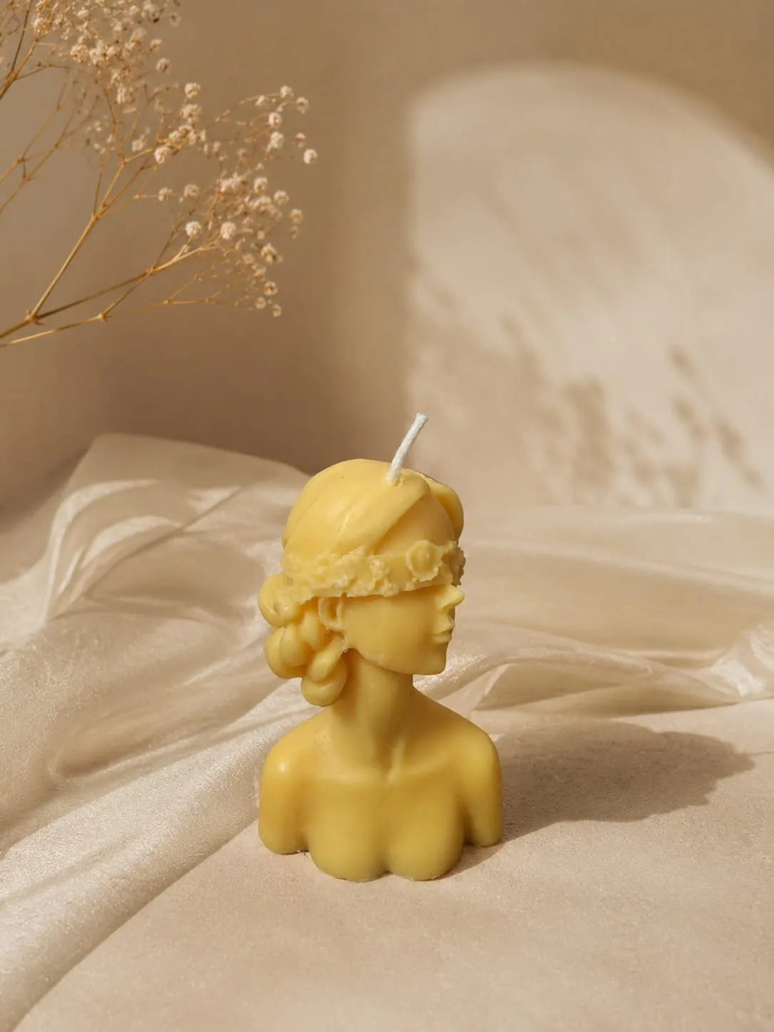 Butter yellow sculpted bust candle on soft draped fabric